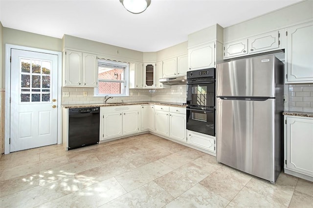 kitchen with a sink, decorative backsplash, stone countertops, under cabinet range hood, and black appliances