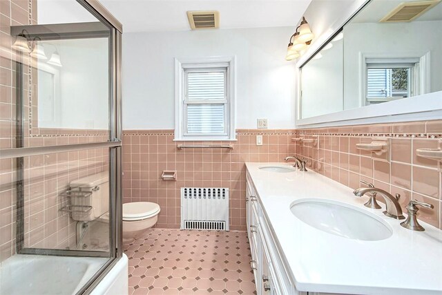 bathroom with radiator heating unit, visible vents, and a sink