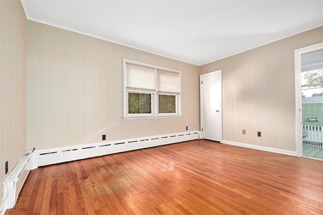 empty room featuring a baseboard radiator, crown molding, light wood-type flooring, radiator, and baseboards