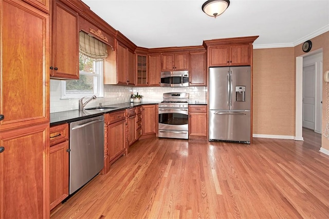 kitchen with brown cabinets, appliances with stainless steel finishes, a sink, and light wood finished floors