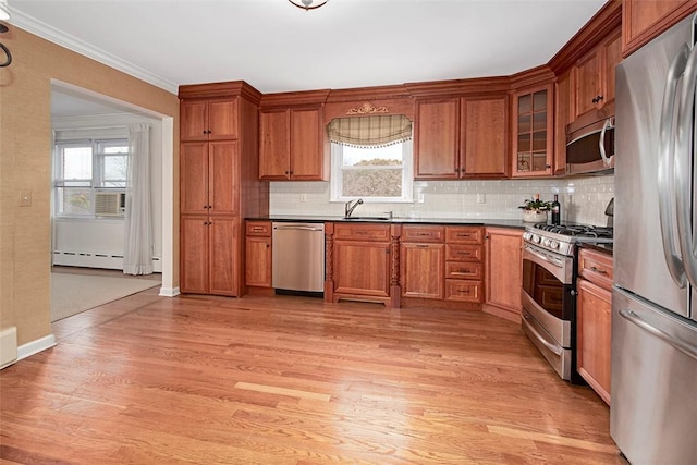 kitchen featuring dark countertops, a baseboard heating unit, light wood-type flooring, a healthy amount of sunlight, and appliances with stainless steel finishes