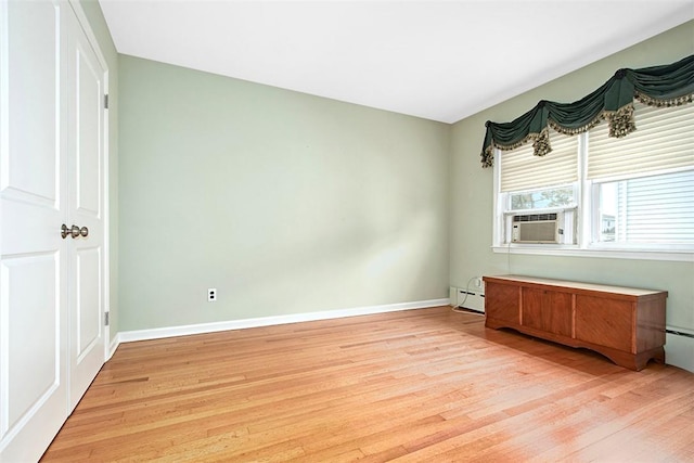 unfurnished bedroom featuring light wood finished floors, cooling unit, baseboards, and a baseboard radiator