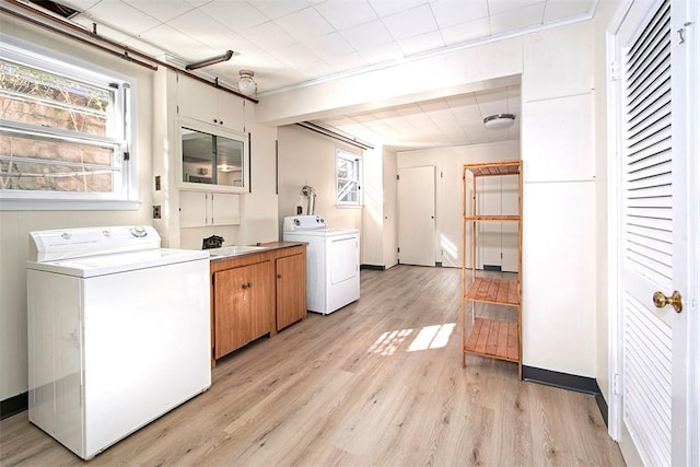 laundry room with light wood-style flooring, a sink, washer and dryer, and cabinet space