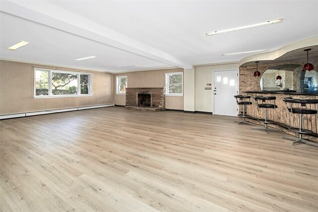 unfurnished living room with a baseboard heating unit, wood finished floors, bar, and a fireplace with raised hearth