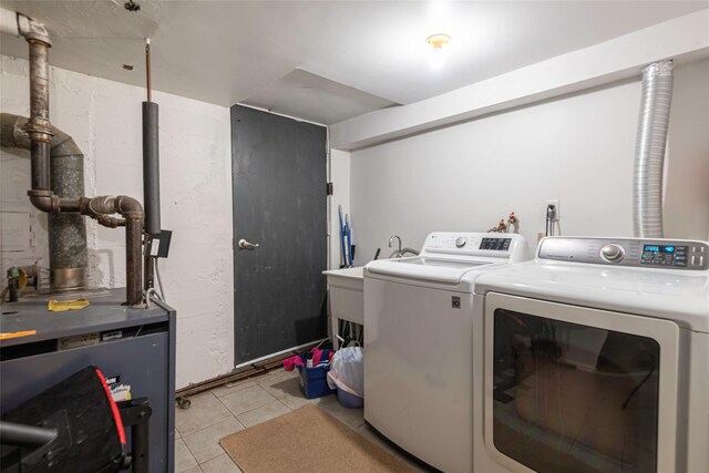 clothes washing area featuring washer and dryer, light tile patterned floors, laundry area, and a heating unit
