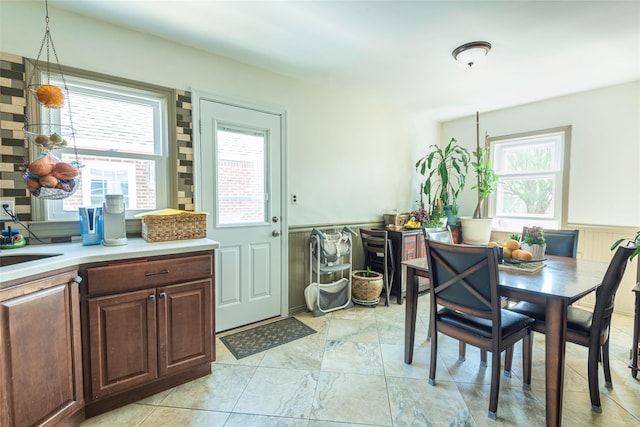 dining space featuring a healthy amount of sunlight and a wainscoted wall