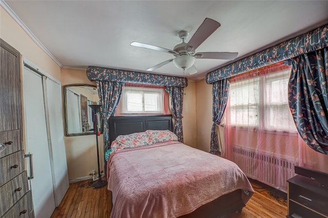 bedroom featuring radiator heating unit, wood finished floors, crown molding, baseboards, and ceiling fan