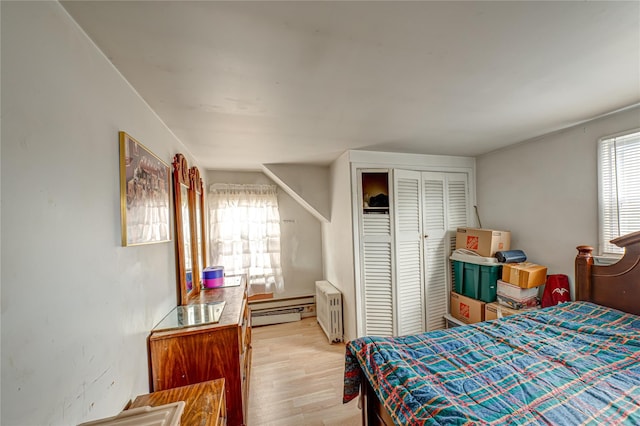 bedroom with light wood-type flooring, radiator heating unit, a closet, and a baseboard radiator