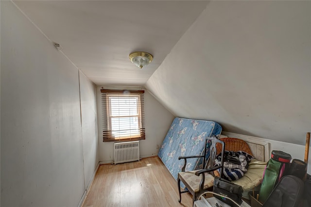additional living space with vaulted ceiling, radiator heating unit, wood finished floors, and baseboards