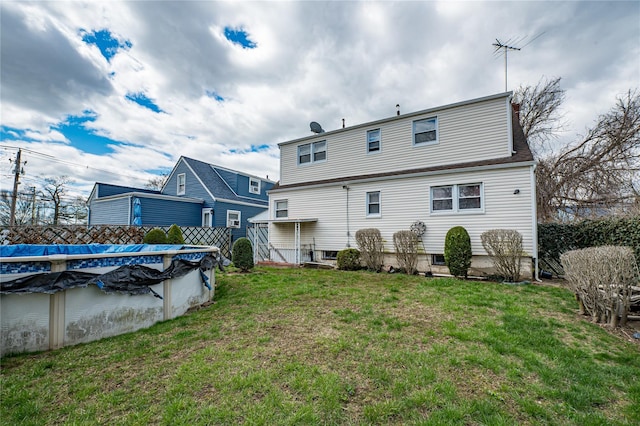 rear view of property featuring a lawn and a covered pool