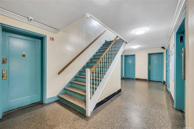 stairs featuring ornamental molding, speckled floor, baseboards, and a textured ceiling