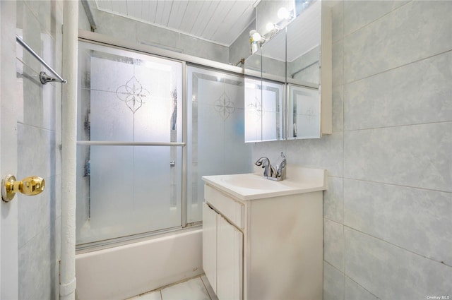 bathroom featuring tile walls, vanity, and enclosed tub / shower combo