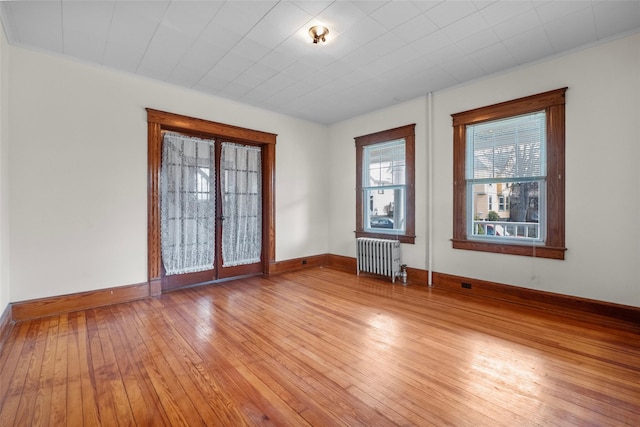 empty room with light wood-style flooring, radiator heating unit, and baseboards
