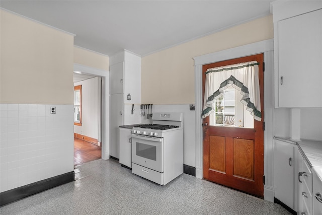 kitchen featuring light countertops, crown molding, white cabinetry, white range with gas stovetop, and wainscoting