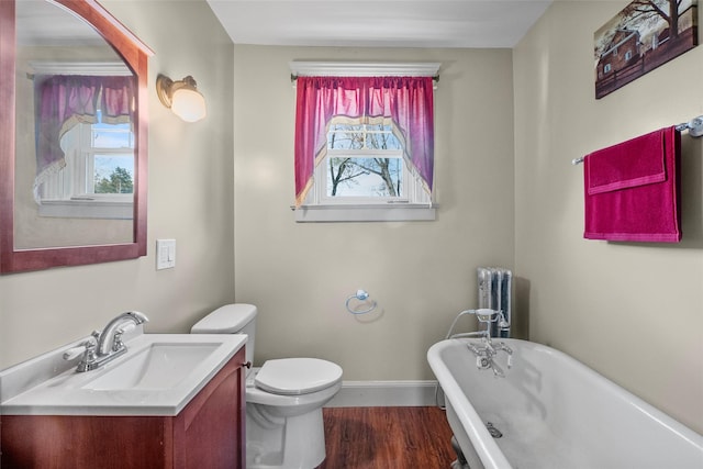bathroom featuring toilet, a freestanding bath, plenty of natural light, and vanity
