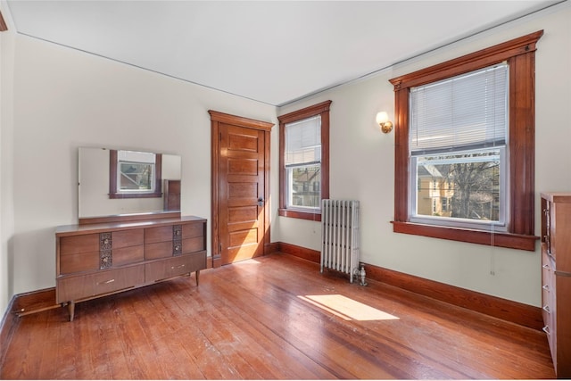 bedroom featuring radiator heating unit, hardwood / wood-style floors, and baseboards