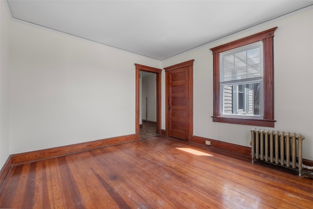 empty room with baseboards, radiator, and hardwood / wood-style flooring
