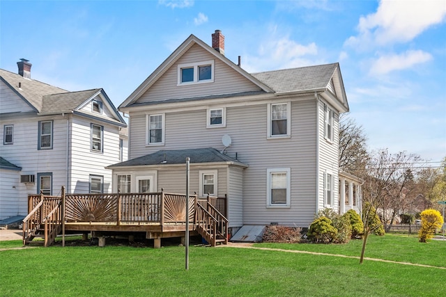 back of house with roof with shingles, a wooden deck, a chimney, and a lawn