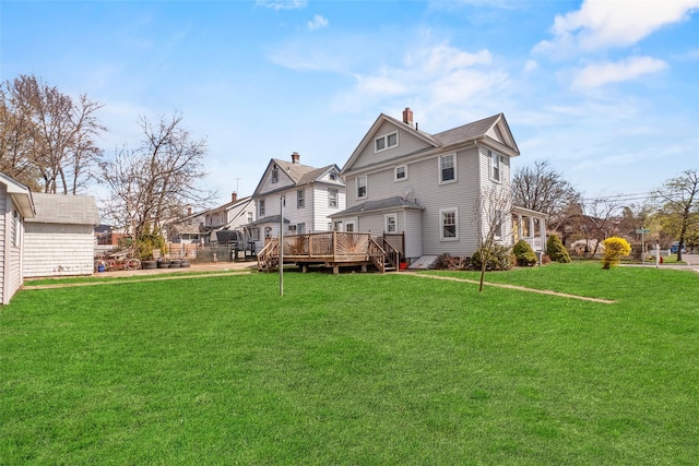 back of property featuring a residential view, a chimney, a deck, and a lawn