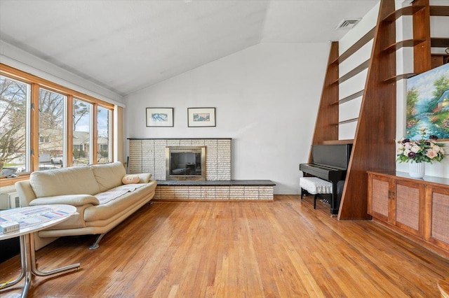 18 Hilary Ln, Westbury, NY 11590 - living room featuring light wood-style flooring, visible vents, a brick fireplace, and lofted ceiling