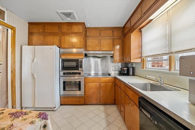18 Hilary Ln, Westbury, NY 11590 - kitchen featuring visible vents, light countertops, under cabinet range hood, brown cabinets, and black appliances