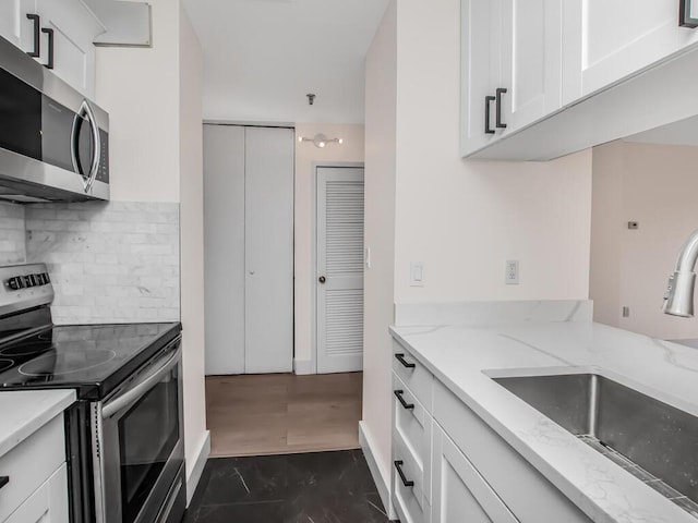 25 Rockledge Ave Unit 117, White Plains, NY 10601 - kitchen with a sink, white cabinetry, backsplash, and appliances with stainless steel finishes