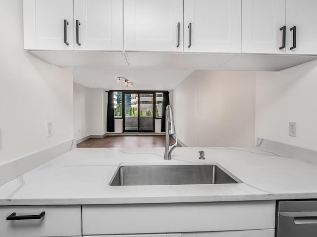 25 Rockledge Ave Unit 117, White Plains, NY 10601 - kitchen with rail lighting, light stone counters, a sink, and white cabinetry