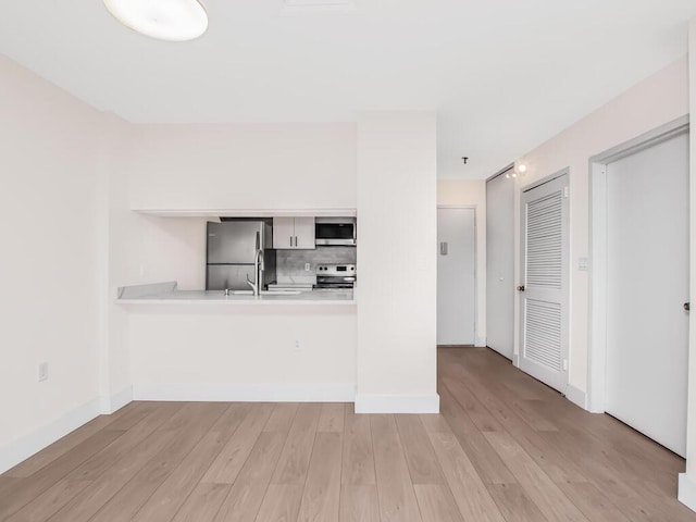 25 Rockledge Ave Unit 117, White Plains, NY 10601 - kitchen with light wood-style flooring, light countertops, appliances with stainless steel finishes, and a peninsula