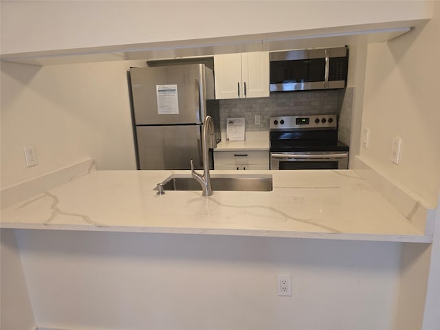 25 Rockledge Ave Unit 117, White Plains, NY 10601 - kitchen with stainless steel appliances, a sink, backsplash, white cabinetry, and light stone counters