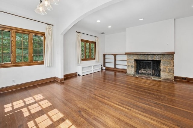 51 Valley Rd, Larchmont, NY 10538 - unfurnished living room with arched walkways, wood finished floors, a stone fireplace, recessed lighting, and a chandelier