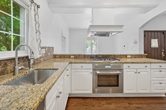 51 Valley Rd, Larchmont, NY 10538 - kitchen featuring appliances with stainless steel finishes, light stone countertops, arched walkways, white cabinets, and dark wood-style floors
