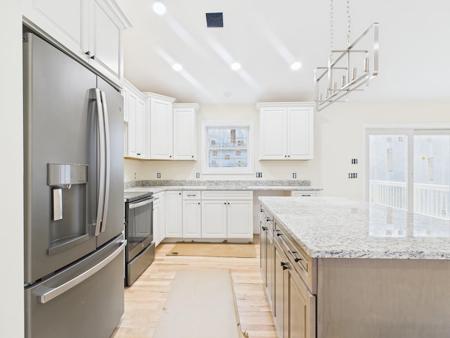 kitchen featuring white cabinets, stainless steel appliances, a center island, and light wood-style flooring