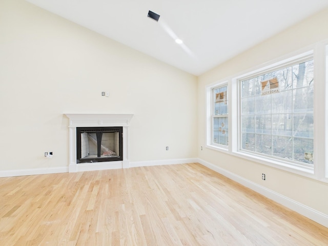 unfurnished living room with lofted ceiling, baseboards, wood finished floors, and a fireplace