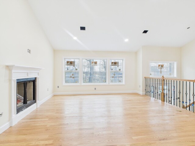 unfurnished living room featuring light wood finished floors, recessed lighting, a fireplace, baseboards, and lofted ceiling