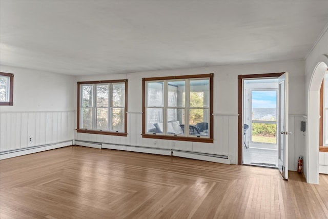 unfurnished living room with a wainscoted wall, plenty of natural light, and arched walkways