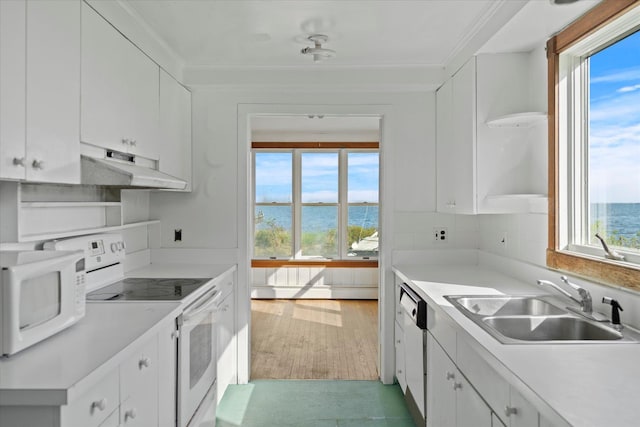 kitchen with white appliances, under cabinet range hood, a sink, a water view, and crown molding