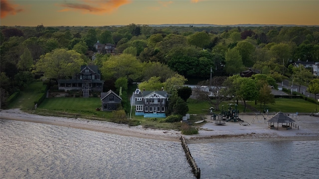 aerial view of property and surrounding area featuring a large body of water and a heavily wooded area