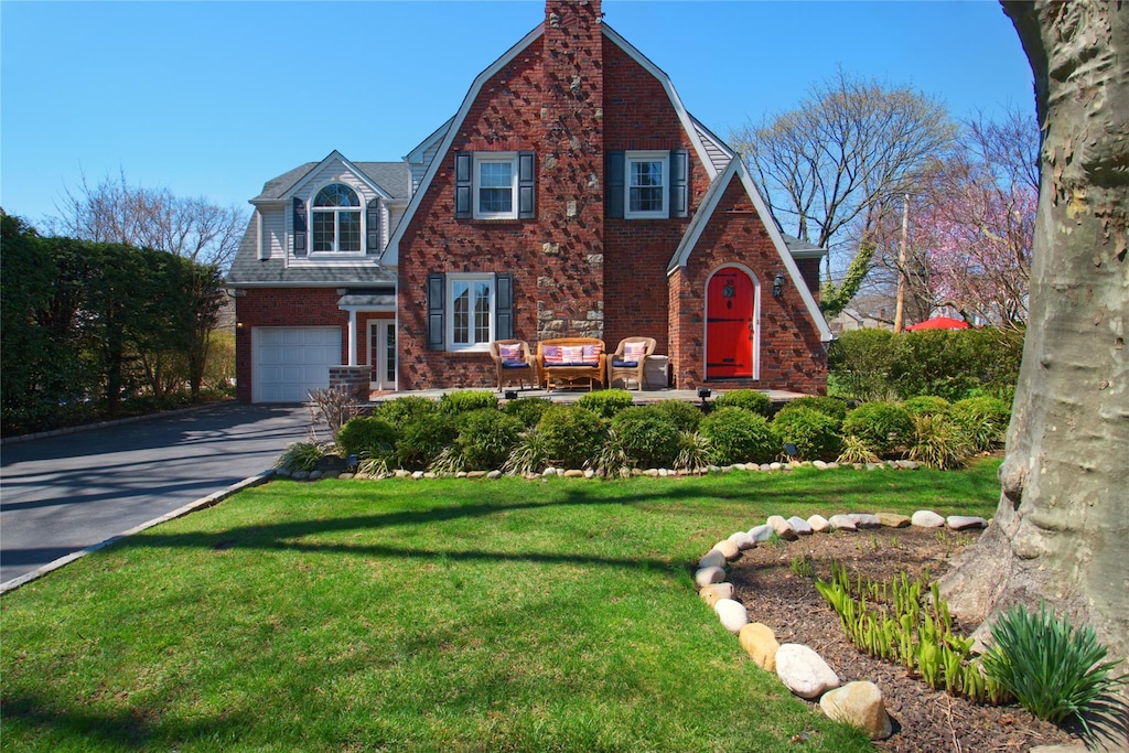 view of front of property with a gambrel roof, a garage, aphalt driveway, and brick siding