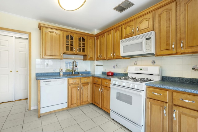 kitchen with tasteful backsplash, a sink, dark countertops, visible vents, and white appliances