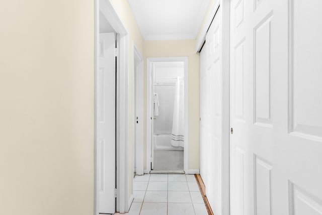 hallway with baseboards, ornamental molding, and light tile patterned flooring