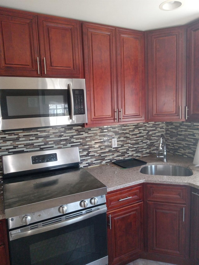 250 Wheeler Rd, Hauppauge, NY 11788 - kitchen featuring light stone counters, backsplash, stainless steel appliances, a sink, and reddish brown cabinets