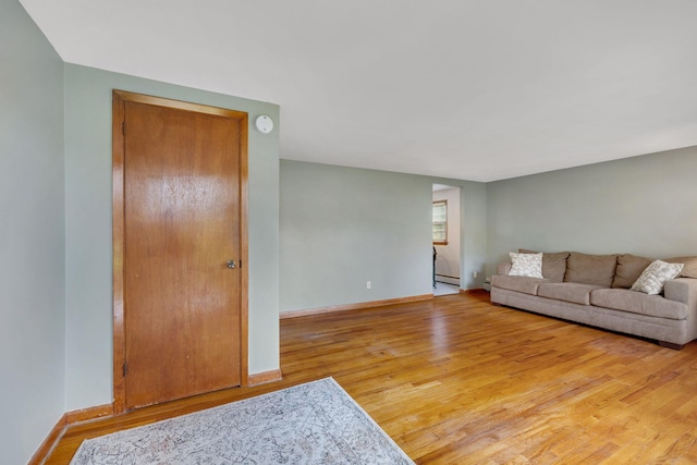living room featuring baseboards, a baseboard heating unit, and light wood-style flooring