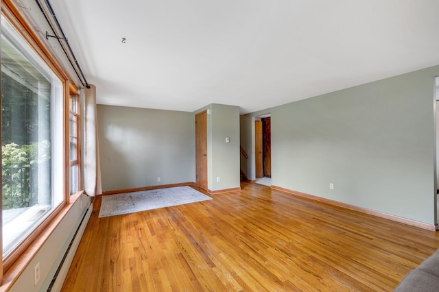 unfurnished room featuring light wood-style floors, baseboards, and a baseboard heating unit