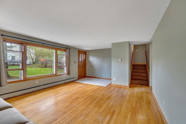 unfurnished living room featuring stairs, baseboards, baseboard heating, and light wood-style flooring