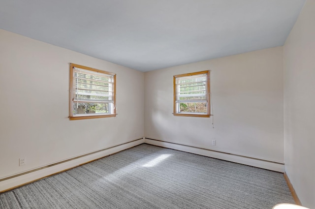carpeted spare room featuring baseboards, a baseboard heating unit, and plenty of natural light