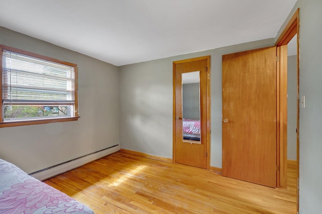 unfurnished bedroom with light wood-style flooring and baseboard heating