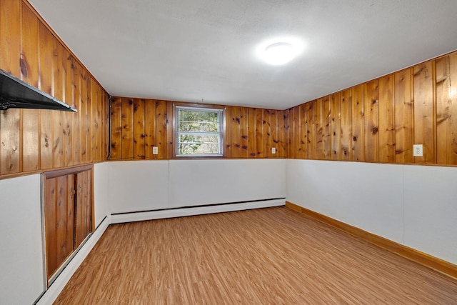 interior space featuring wooden walls, baseboard heating, and wood finished floors