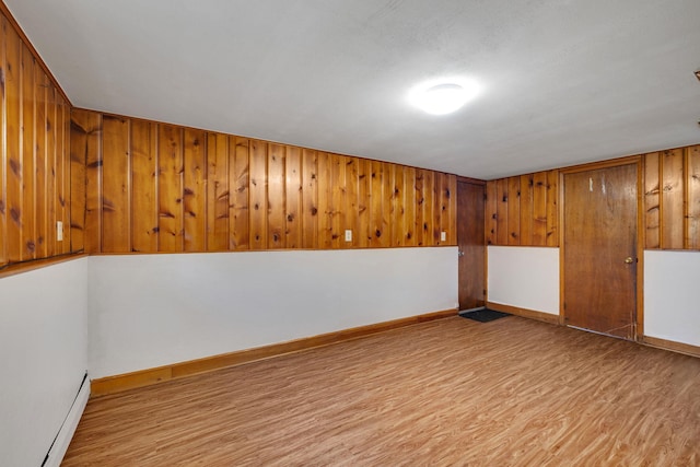 finished basement with baseboard heating, baseboards, and wood finished floors