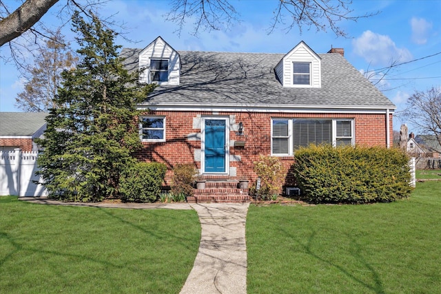 cape cod home featuring brick siding, a shingled roof, a front lawn, and a chimney