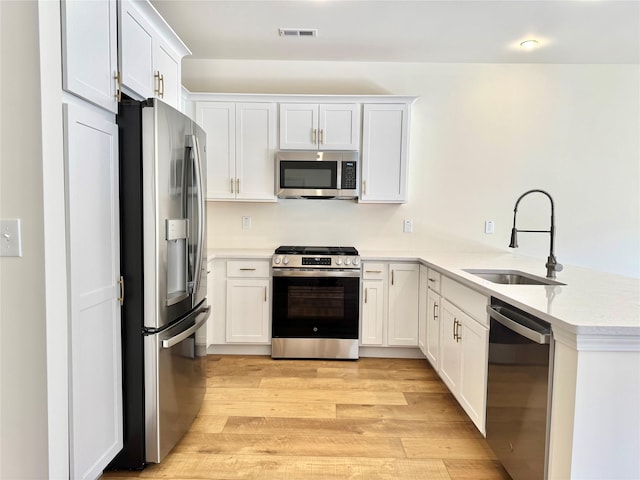 kitchen featuring light wood-style flooring, light countertops, visible vents, appliances with stainless steel finishes, and a sink